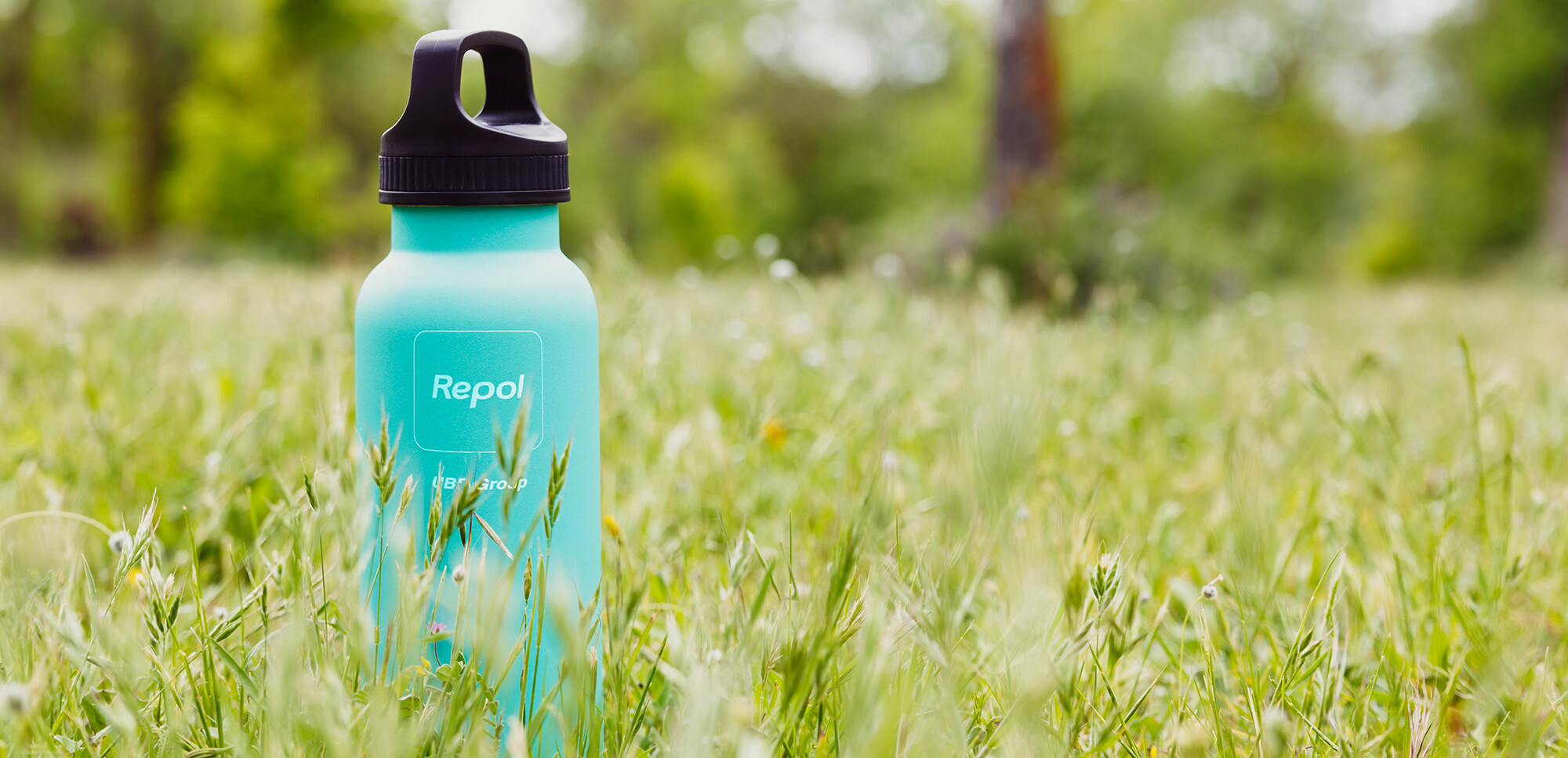 Bottle with Repol logo standing on a meadow 