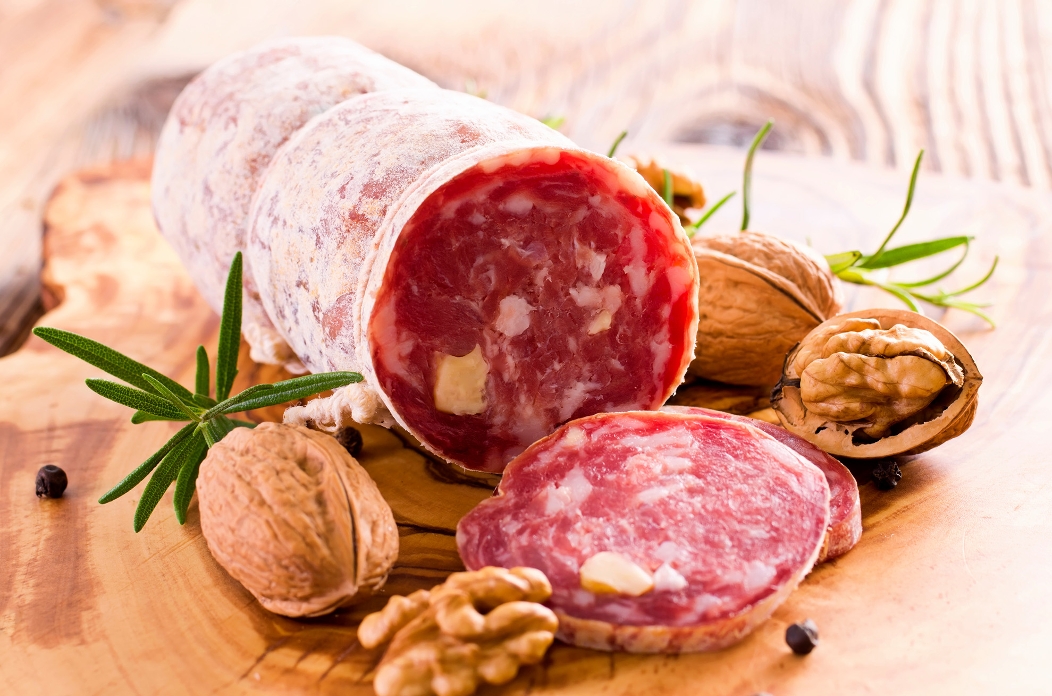 Bild von aufgeschnittener Salami und Walnüssen auf einem Holzbrett